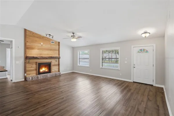 a view of an empty room with wooden floor fireplace and a window