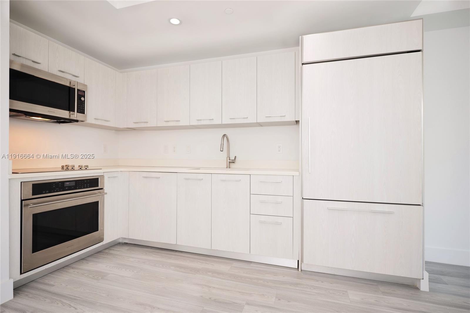 45 Southwest 9th Street, Unit 1504 Miami, FL 33130 - Photo 6 of 33 a kitchen with a refrigerator stove and white cabinets