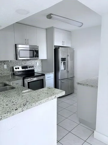 a kitchen with stainless steel appliances granite countertop a sink refrigerator and microwave