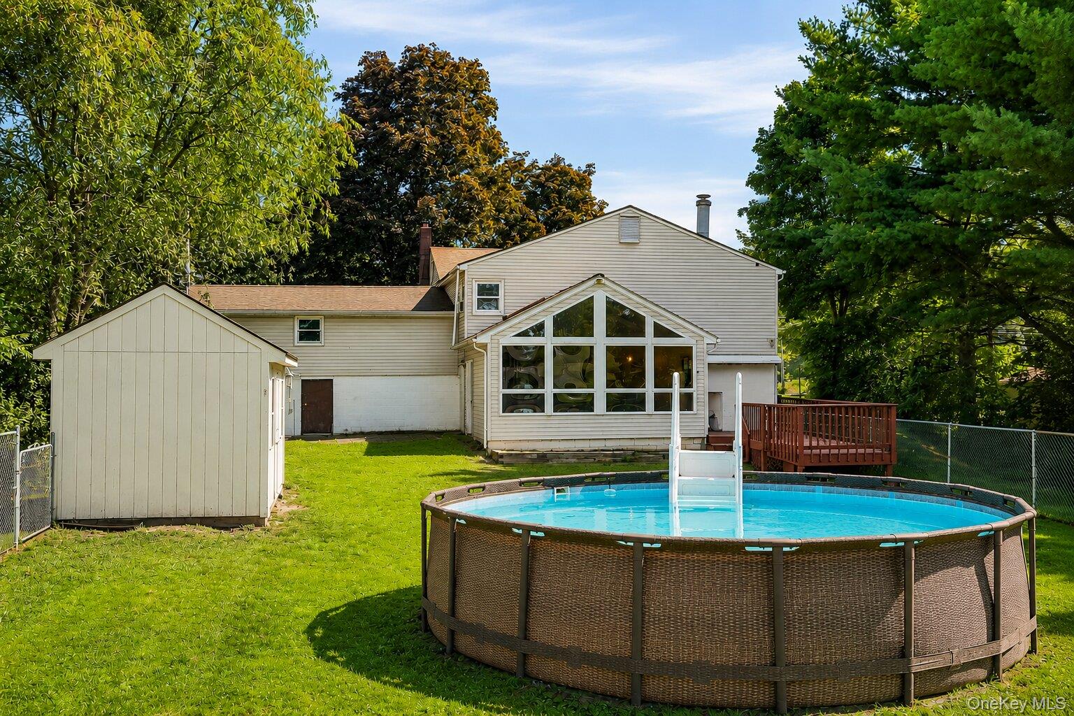 49 Chase Road Wallkill, NY 12589 - Photo 31 of 32 Spacious fenced backyard with an above-ground pool, storage shed, deck, and enclosed rear addition overlooking the property.