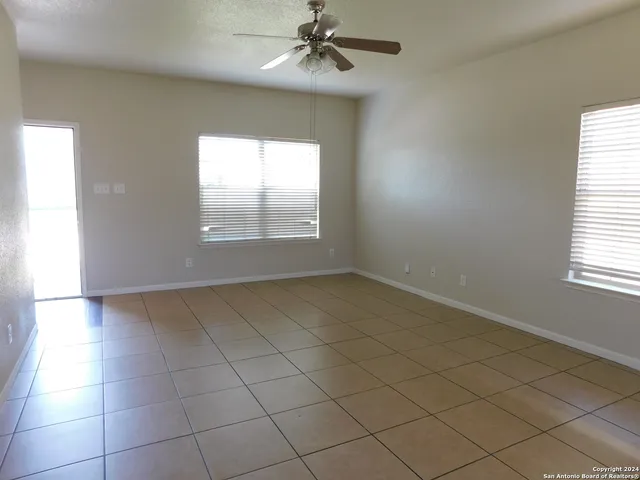 an empty room with a chandelier fan and windows