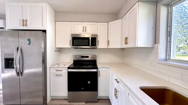 a kitchen with cabinets stainless steel appliances and a window