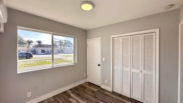 a view of an empty room with wooden floor and a window