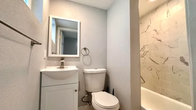a bathroom with a toilet sink vanity tub and mirror