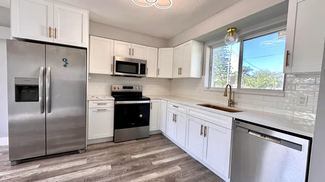 a kitchen with stainless steel appliances granite countertop a refrigerator sink and microwave