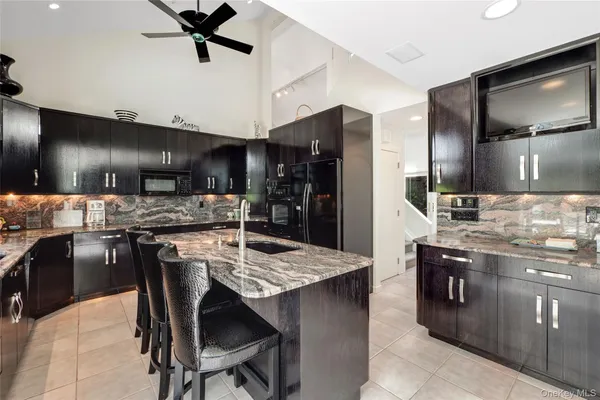 a kitchen with stainless steel appliances kitchen island granite countertop a table chairs sink and refrigerator