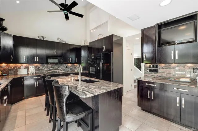 a kitchen with stainless steel appliances kitchen island granite countertop a table chairs sink and refrigerator