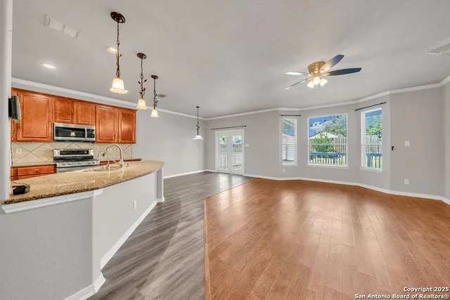 a large kitchen with hardwood floor a large window and stainless steel appliances