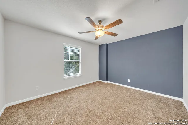a view of an empty room and chandelier fan