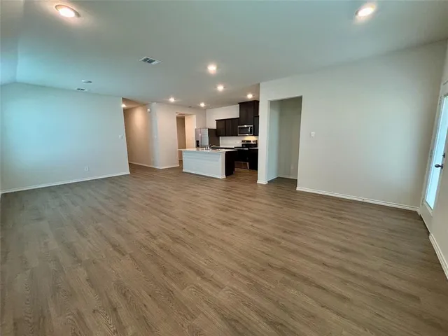 a view of kitchen with kitchen island wooden floor center island and stainless steel appliances