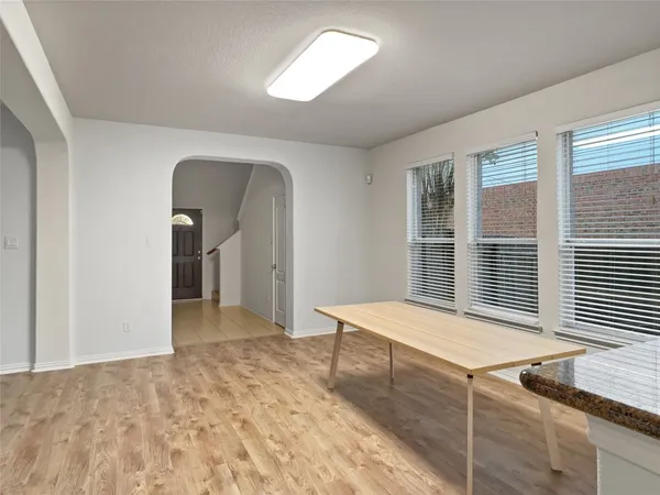 a view of an empty room with window and hardwood floor