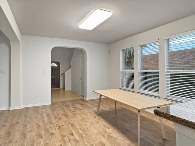a view of an empty room with window and hardwood floor