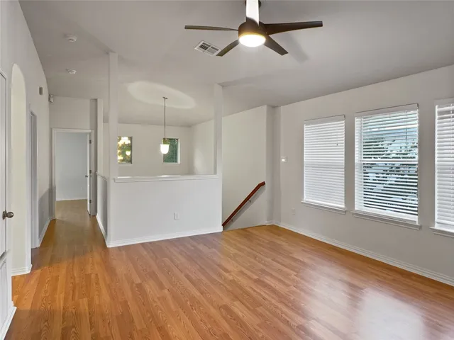 a view of empty room with wooden floor and fan