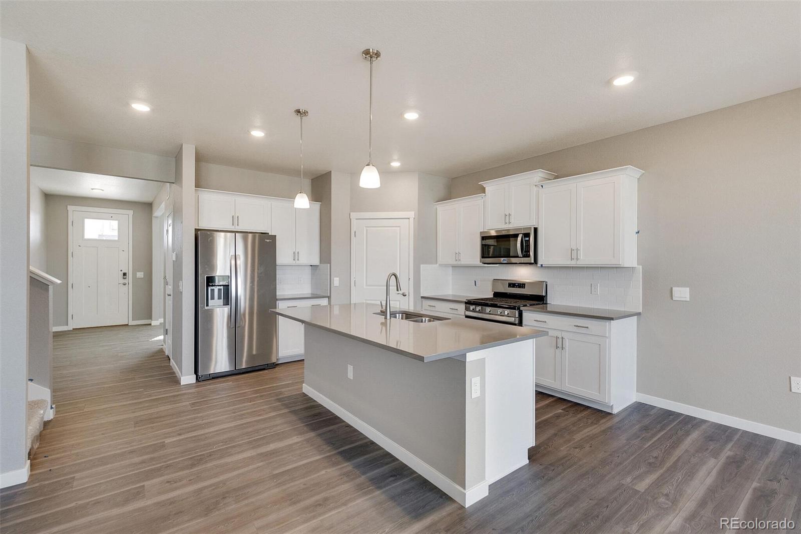 18358 Field Mint Point Parker, CO 80134 - Photo 12 of 34 a kitchen with stainless steel appliances granite countertop a refrigerator a sink dishwasher a stove and white cabinets with wooden floor