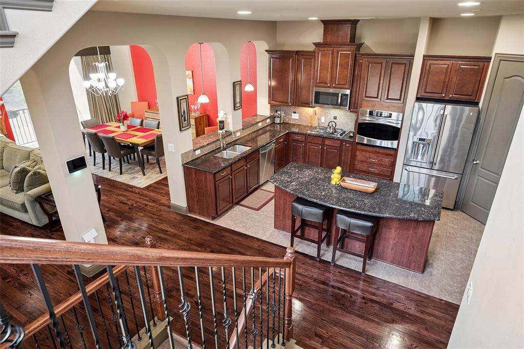 835 Rockingham Drive Irving, TX 75063 - Photo 13 of 27 a kitchen with stainless steel appliances wooden floors wooden cabinets dining table and chairs