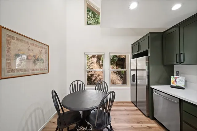 a kitchen with stainless steel appliances a dining table chairs and refrigerator