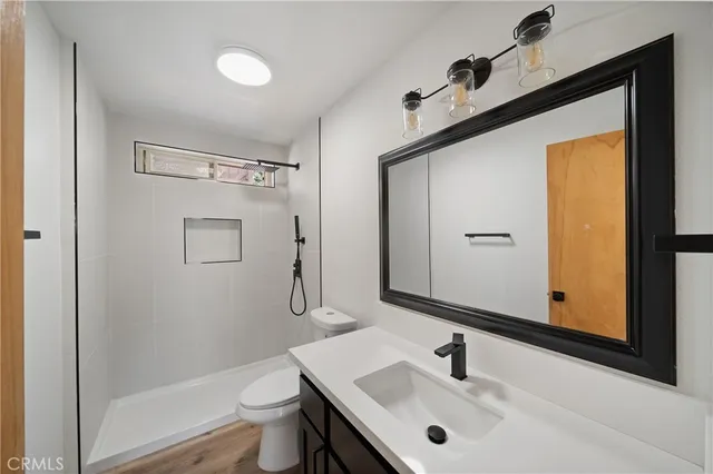 a bathroom with a sink a toilet a mirror and shower