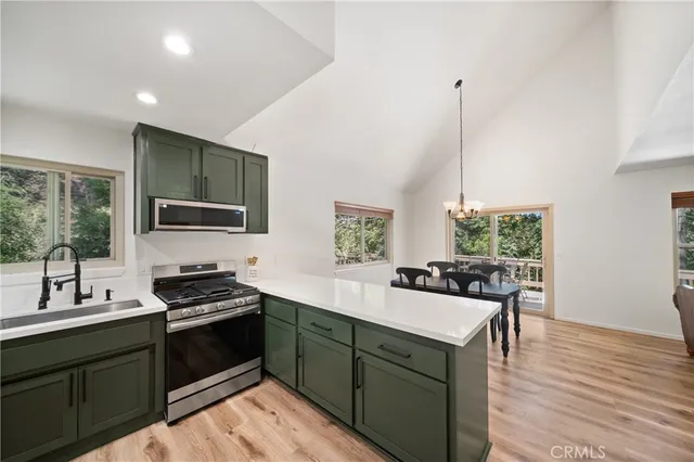 a kitchen with stainless steel appliances a sink stove and wooden floor