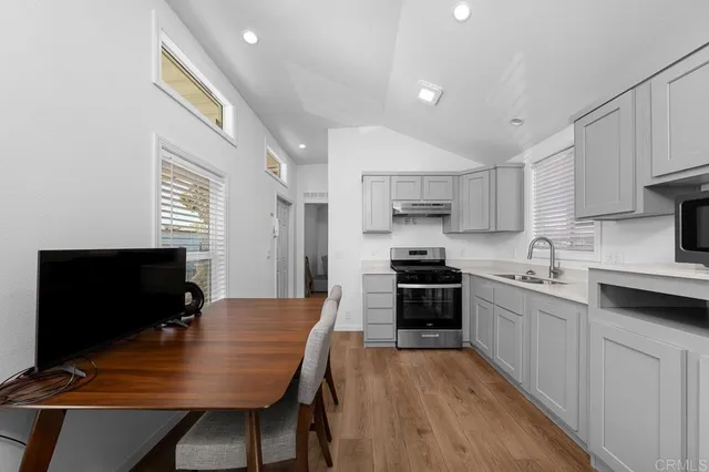 a kitchen with stainless steel appliances granite countertop a stove top oven a sink dishwasher a dining table and chairs with wooden floor