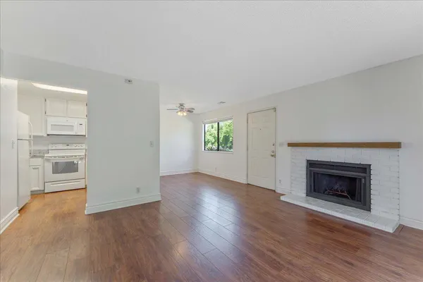 an empty room with wooden floor a fireplace and windows