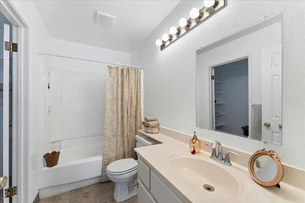 a bathroom with a granite countertop toilet a sink and a mirror