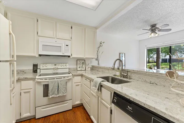 a kitchen with granite countertop a sink stainless steel appliances and white cabinets
