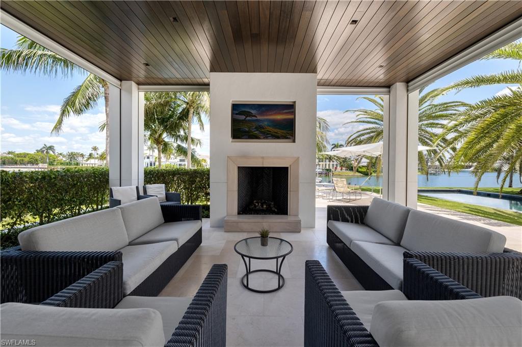 3655 Fort Charles Drive Naples, FL 34102 - Photo 35 of 50 a living room with furniture a fireplace and a floor to ceiling window