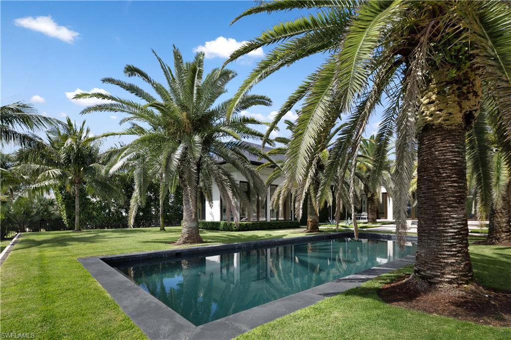 3655 Fort Charles Drive Naples, FL 34102 - Photo 39 of 50 a view of swimming pool with a garden and trees