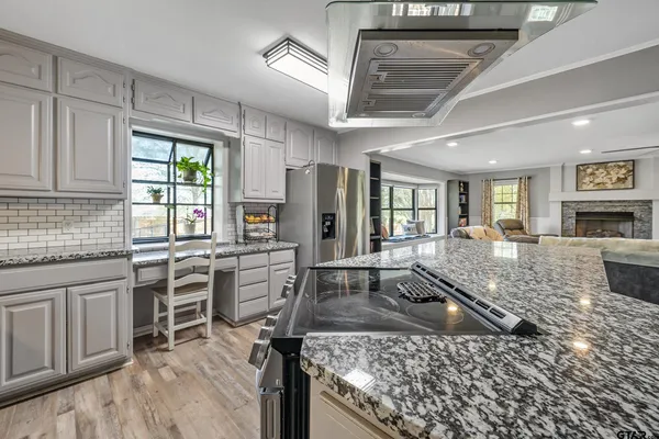 a kitchen with kitchen island granite countertop a stove refrigerator and cabinets