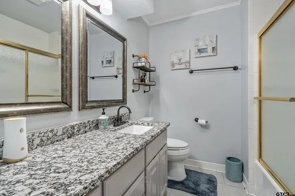 a bathroom with a granite countertop sink toilet and mirror