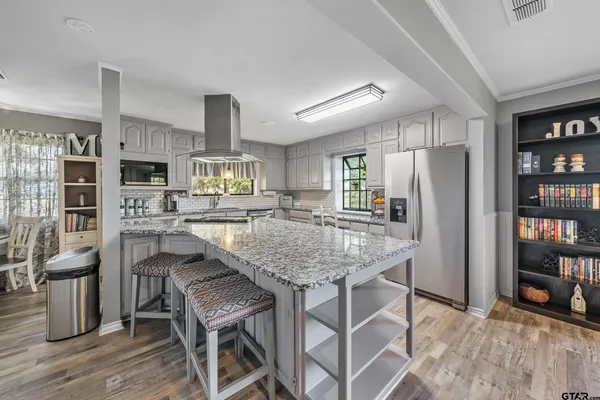 a kitchen with stainless steel appliances granite countertop a table chairs and a refrigerator