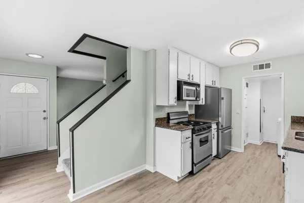 a kitchen with stainless steel appliances a refrigerator stove and wooden floor