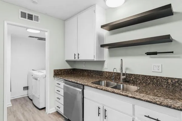 a kitchen with granite countertop white cabinets and a sink