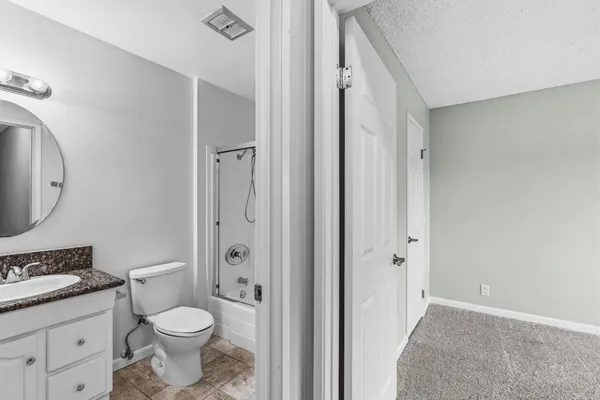 a bathroom with a granite countertop toilet a sink and a mirror