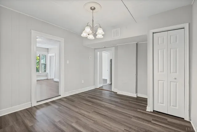 an empty room with wooden floor cabinet and windows
