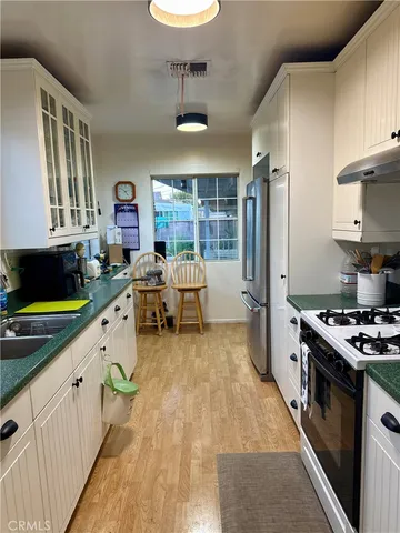 a kitchen with stainless steel appliances granite countertop a stove a sink dishwasher and a dining table with cabinets