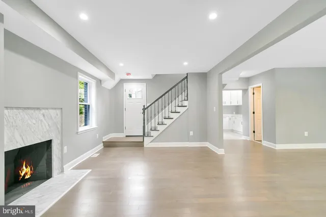 a view of an empty room with wooden floor fireplace and a window
