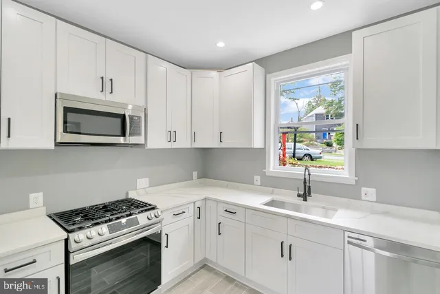 a kitchen with cabinets appliances a sink and a window