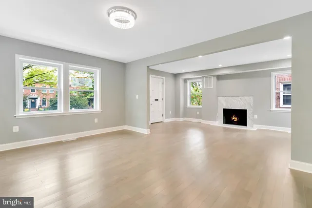 an empty room with windows and fireplace