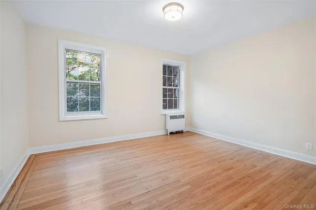 an empty room with wooden floor closet and windows