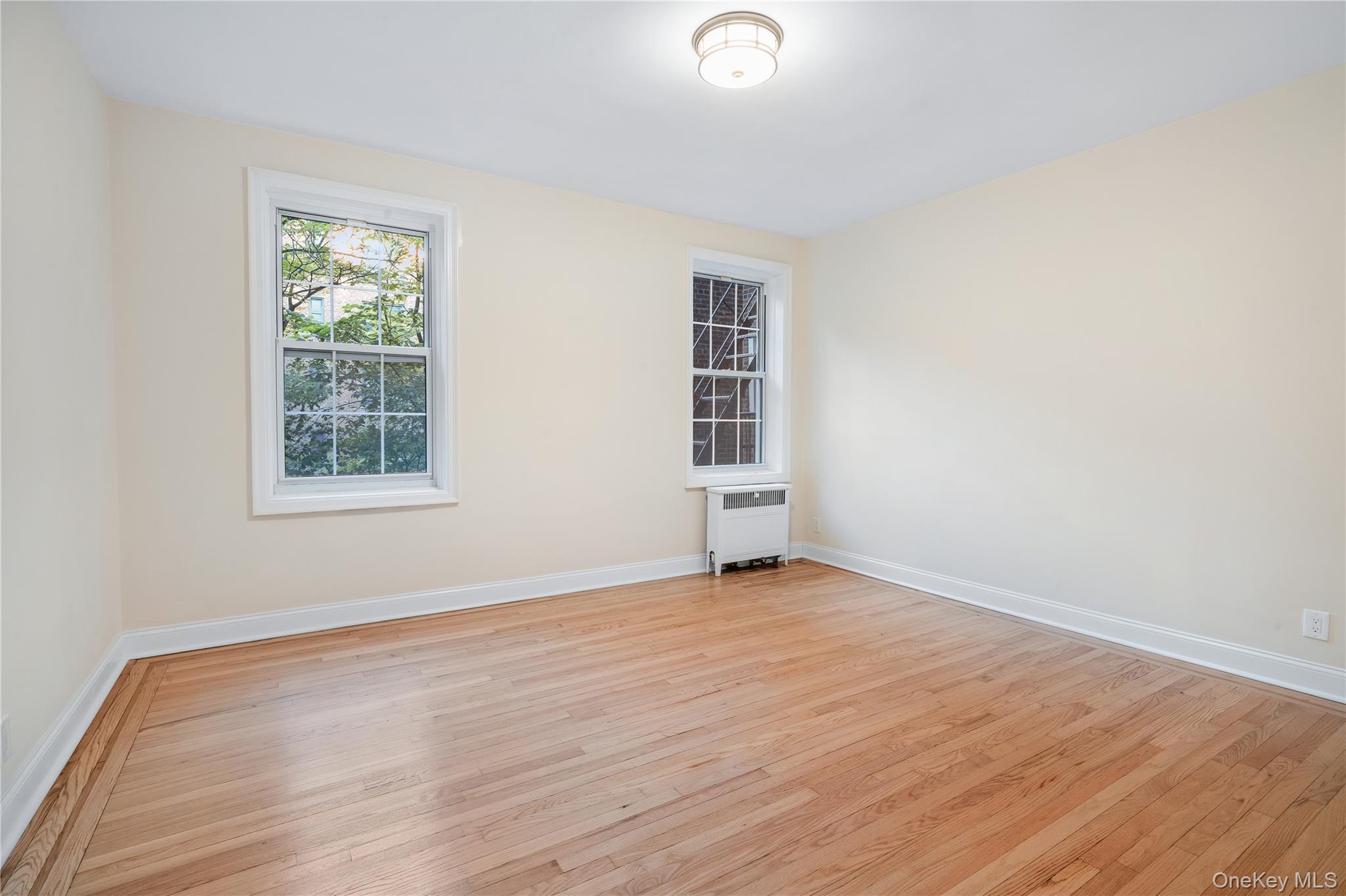 110-07 73rd Road, Unit 3K Queens, NY 11375 - Photo 8 of 21 an empty room with wooden floor closet and windows