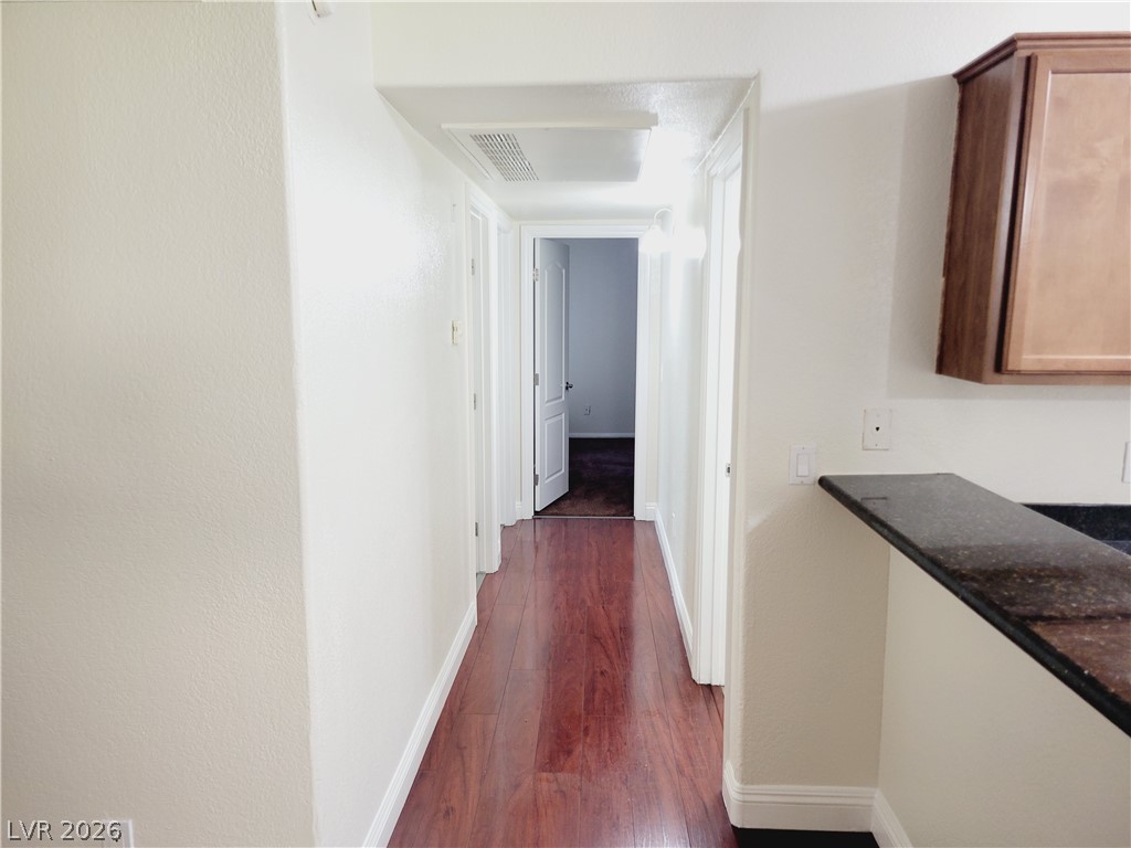 9325 West Desert Inn Road, Unit 178 Las Vegas, NV 89117 - Photo 8 of 20 Rich wood-plank flooring guides the eye through a classic hallway connecting distinct living areas.