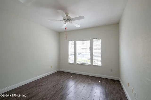 an empty room with wooden floor and fan