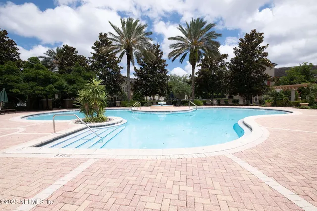 a view of a swimming pool with a chair and palm trees