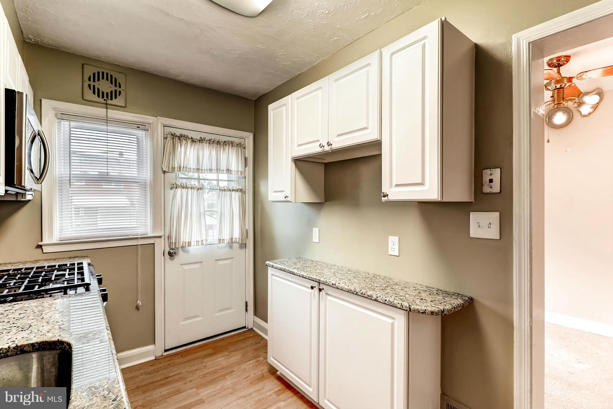 2102 Redthorn Road Baltimore, MD 21220 - Photo 3 of 30 a kitchen with stainless steel appliances granite countertop a stove a sink and a refrigerator with wooden floors