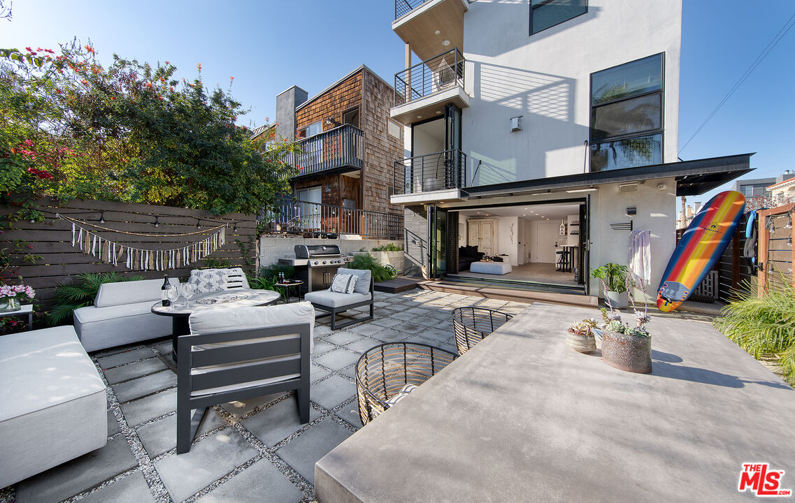 5317 Pacific Avenue Marina del Rey, CA 90292 - Photo 6 of 41 a view of a patio with couches table and chairs under an umbrella with a fire pit