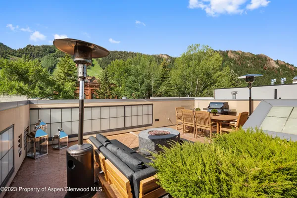 a roof deck with table and chairs under an umbrella with large trees
