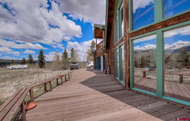 a hallway with a lots of white furniture a rug and a chandelier