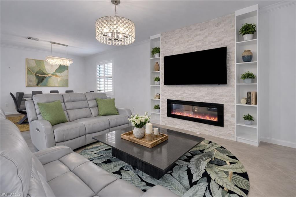 17609 Ashcomb Way Estero, FL 33928 - Photo 3 of 40 Living area featuring ornamental molding, hanging lights, a fireplace, and built in shelves