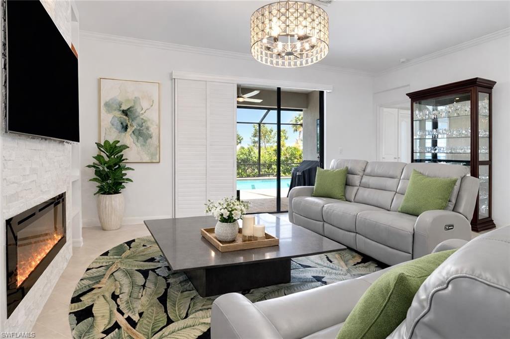 17609 Ashcomb Way Estero, FL 33928 - Photo 6 of 40 Living room with ceiling fan, suspended lighting, ornamental molding, and a fireplace